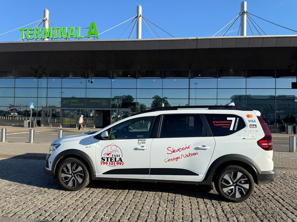 Biała Dacia Jogger Taxi Stela przed terminalem A lotniska Katowice-Pyrzowice.
