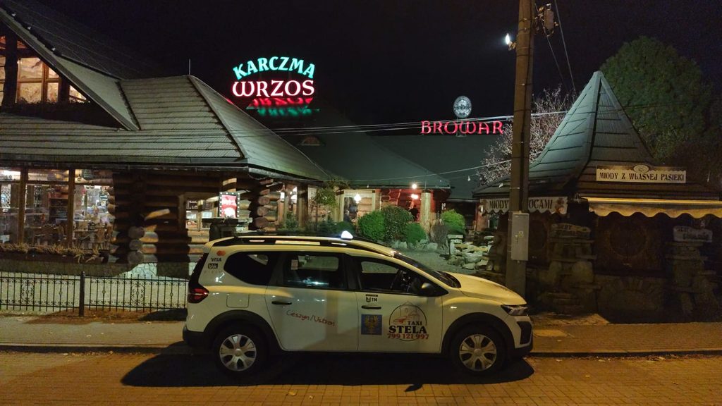 Biała Dacia Jogger Taxi Stela przed Karczmą Wrzos nocą.